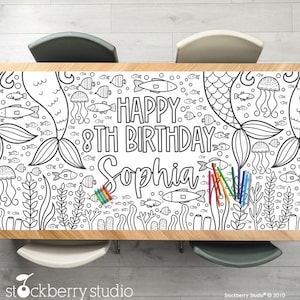 May include: A black and white coloring table cloth with a mermaid theme. It says "Happy 8th Birthday Sophia" and has mermaids, fish, and jellyfish.