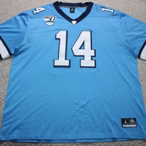 May include: A light blue football jersey with white and navy blue trim. The number "14" is printed in white on the front of the jersey. The jersey has a navy blue collar and a white stripe on each sleeve. The jersey is a size XL.