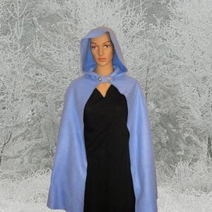 May include: A light blue hooded cape with a black dress underneath. The cape has a button closure at the neck.