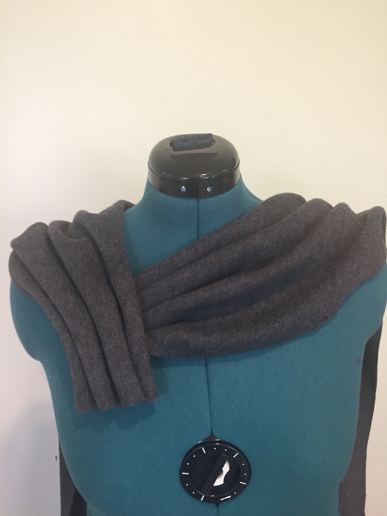 Puede incluir: Una bufanda gris oscuro drapeada sobre un maniqu&iacute; turquesa. La bufanda est&aacute; hecha de un material suave y texturizado, doblada para mostrar su forma y ca&iacute;da. El maniqu&iacute; tiene un cuello negro y un dial en la parte delantera.