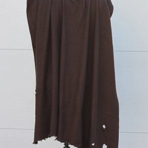 Puede incluir: Una capa marr&oacute;n oscuro con cuello en V, colocada sobre un maniqu&iacute;. La tela tiene un aspecto desgastado con varios agujeros cerca del borde inferior. La capa es probablemente para disfraces o cosplay.