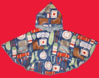 May include: A blue hooded poncho featuring a repeating pattern of camping-related illustrations. The design includes brown hiking boots, first aid kits, backpacks, and compasses. Ideal for outdoor activities, the poncho has a cosy, hooded design.