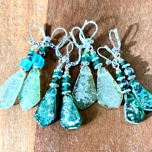 May include: A set of four pairs of earrings featuring green and blue sea glass with silver hooks and beads.
