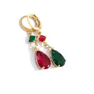 May include: Gold dangle earrings with red and green teardrop-shaped crystals and square crystals.