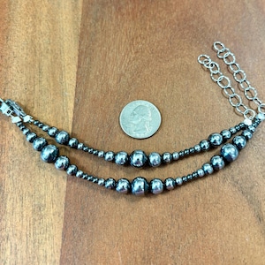 May include: A double-strand bracelet with silver chain links and large, round, dark gray beads.
