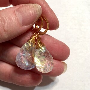 May include: A pair of iridescent crystal earrings with gold wire wrapping and gold hoop closures.