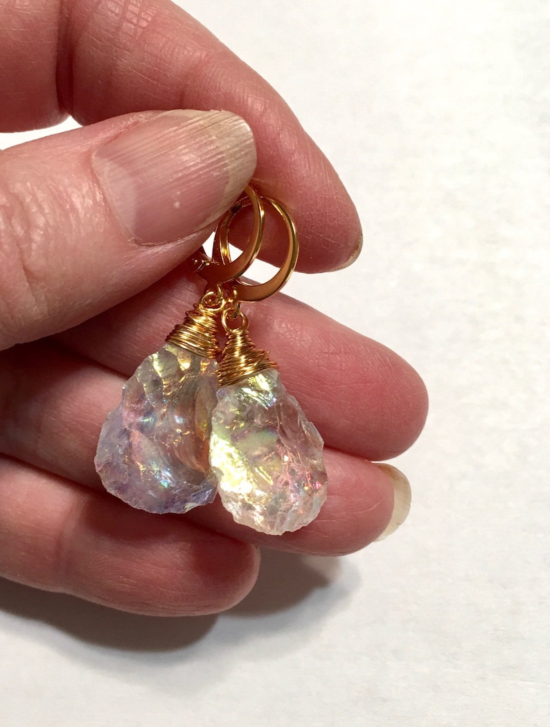 May include: A pair of iridescent crystal earrings with gold wire wrapping and gold hoop closures.