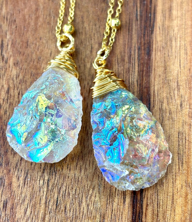 Pu&ograve; includere: Due ciondoli a goccia di cristallo iridescente su catene dorate. I cristalli sono avvolti in filo d'oro e hanno un bagliore arcobaleno.