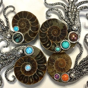 May include: Four silver octopus sculptures with ammonite fossils and colorful gemstones. Each octopus has a different colored gemstone in the center of its head.