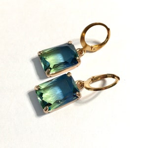May include: A pair of gold earrings with green and blue ombre rectangular gemstones.