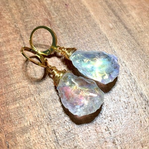 May include: Gold wire wrapped iridescent crystal earrings. The crystals are teardrop shaped and have a rainbow sheen.