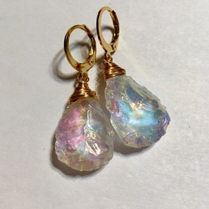 May include: Gold hoop earrings with iridescent crystal teardrop dangles. The crystals are wrapped in gold wire.
