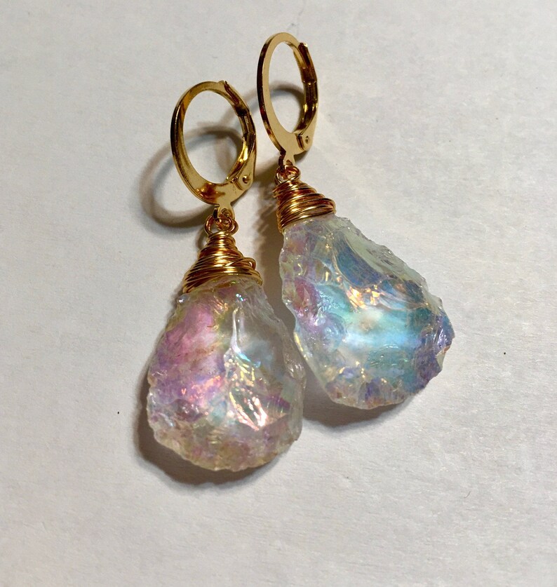 May include: Gold hoop earrings with iridescent crystal teardrop dangles. The crystals are wrapped in gold wire.