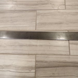 May include: A long, flat, silver metal bar.