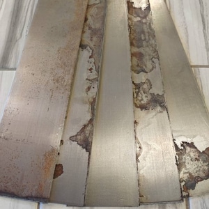 May include: Five metal strips with a silver finish and rust spots. The strips are arranged in a fan shape.