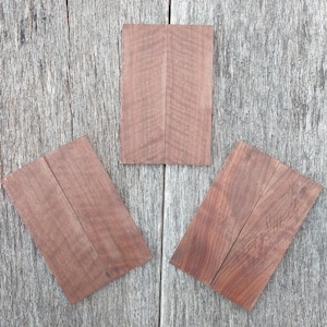 Puede incluir: Tres piezas de madera, cada una con un color marrón natural y un patrón de veta. Las piezas de madera están dispuestas en forma triangular sobre una superficie de madera gris.