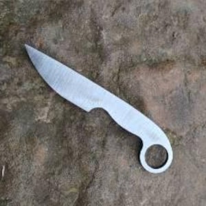May include: A small, silver knife with a rounded handle and a hole in the center. The blade is slightly curved and has a sharp point.