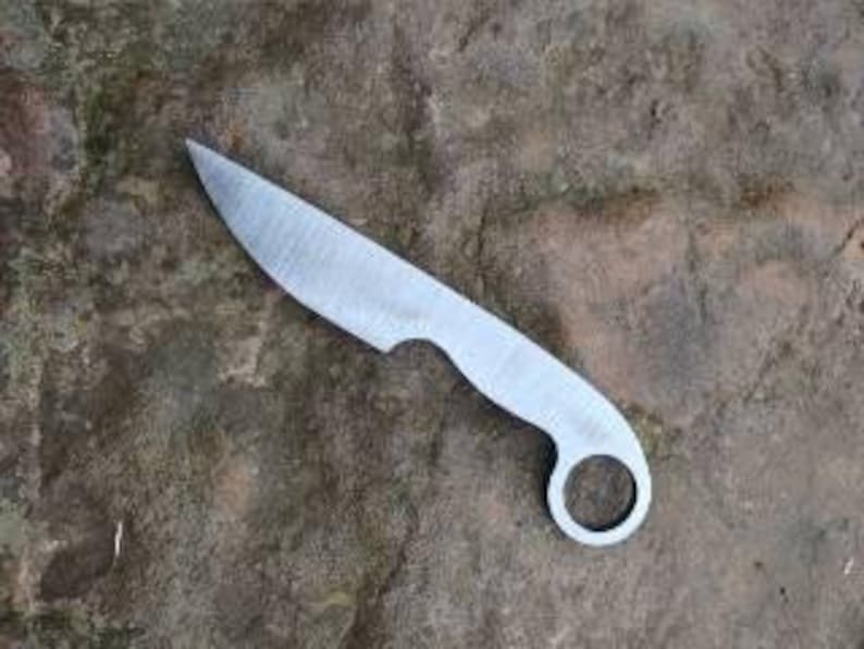 May include: A small, silver knife with a rounded handle and a hole in the center. The blade is slightly curved and has a sharp point.