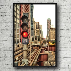 May include: A red traffic light with the words "LP2 110" on it is positioned at a railroad crossing. A train is passing by in the background. The scene is set in an urban environment with tall buildings.