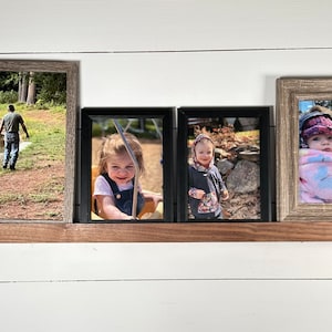May include: Four framed photographs on a wooden shelf. The photos show a father and daughter walking by a lake, a young girl on a swing, a young girl in a wooded area, and a baby being held by a person.