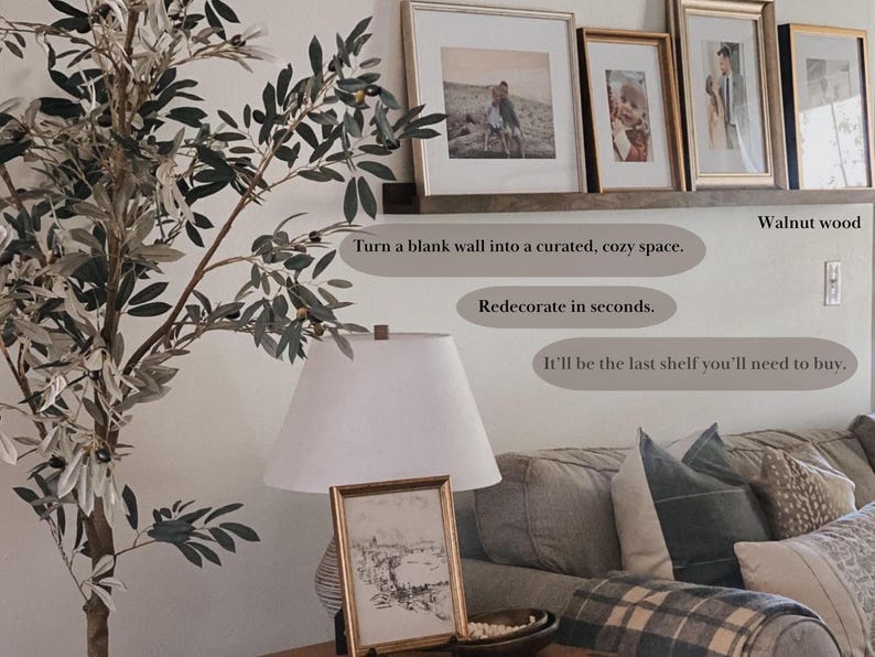 May include: A walnut wood shelf with a white background. The shelf is decorated with framed pictures and a potted olive tree. The text "Turn a blank wall into a curated, cozy space. Redecorate in seconds. It'll be the last shelf you'll need to buy." is written on the wall.