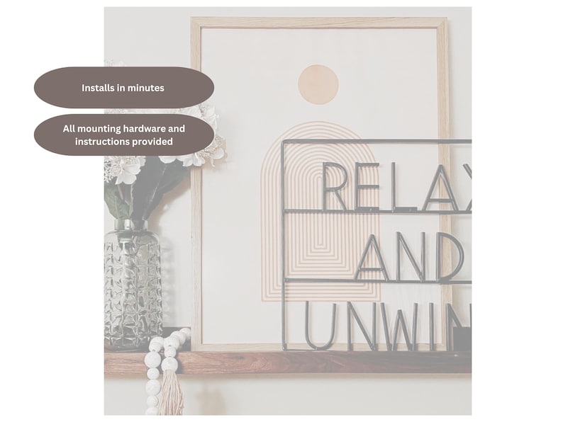 May include: A framed artwork with a neutral color palette, featuring a geometric design and the words "RELAX AND UNWIND" in black metal lettering. A vase with flowers and decorative beads are on a wooden shelf below.