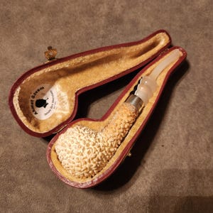 May include: A white briar pipe with a textured surface, in a red velvet lined case. The pipe is labeled "Annet Govern" and "Black Mountain".