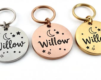 May include: Three round pet ID tags in silver, rose gold, and gold. Each tag features the name "Willow" in a script font, along with a crescent moon and star design. The tags are attached to key rings.