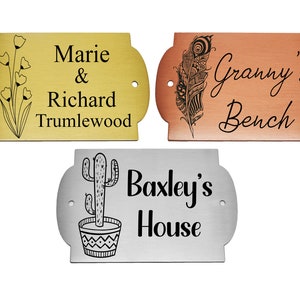 May include: Three engraved metal plaques with different designs. The top left plaque is gold with a floral design and the text "Marie & Richard Trumlewood". The top right plaque is copper with a feather design and the text "Granny's Bench". The bottom plaque is silver with a cactus design and the text "Baxley's House".