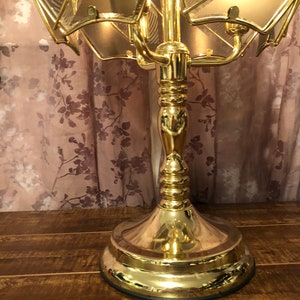 May include: A gold-toned table lamp with a multi-tiered, geometric, glass shade. The lamp has a decorative, ornate base.