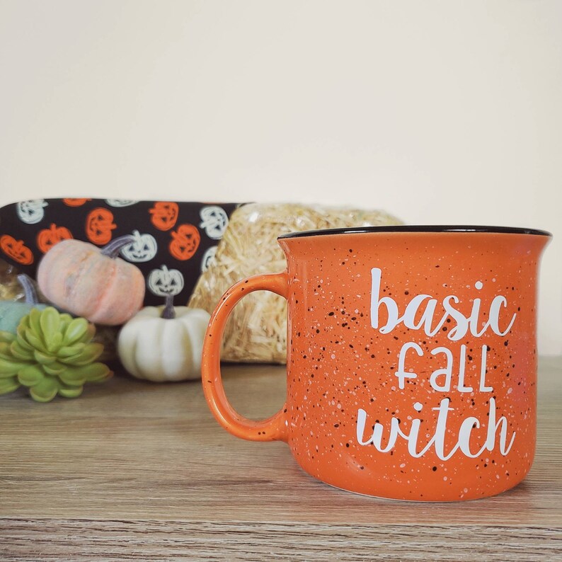May include: Orange speckled ceramic mug with a black rim and a white inscription that reads "basic fall witch".