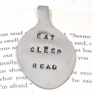 May include: A silver spoon bookmark with the words "Eat, Sleep, Read" engraved on it.