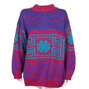 Könnte beinhalten: Ein rosa, blauer und lilafarbener Pullover mit geometrischem Muster. Der Pullover hat einen hohen Kragen und lange Ärmel.
