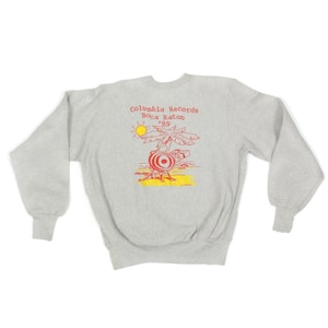 May include: A light grey sweatshirt with a crew neck and long sleeves. The front features a red and yellow graphic of a palm tree, sun, and a record player with the text "Columbia Records Boca Raton '89".