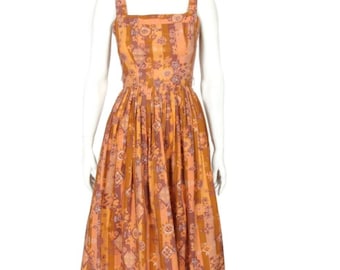 May include: A sleeveless midi dress with a square neckline and a fitted bodice. The dress is made of a lightweight fabric with a colorful floral and geometric print in shades of orange, pink, and brown.