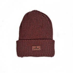 May include: A maroon knitted beanie with a brown leather patch that says "KNITS&NAPS".