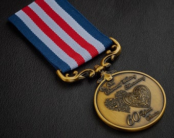 May include: A gold-colored medal with a blue, white, and red ribbon. The medal features a design of two intertwined hearts with intricate details and the text "On Our Diamond Wedding Anniversary 60 Years Service".