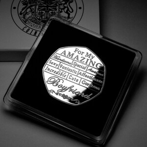 May include: A silver coin with the words "For My Amazing Boyfriend" and a list of positive adjectives surrounding the words. The coin is in a black velvet box.