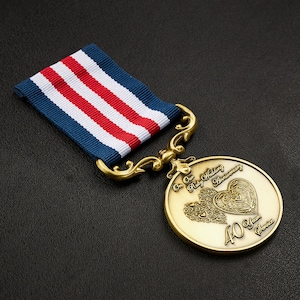 May include: A gold medal with a red, white and blue ribbon. The medal features two intertwined hearts with a decorative design and the text "Our Ruby Wedding Anniversary 40 Years Service".