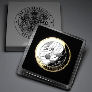 以下が含まれることがあります： 惑星と星が描かれたスタイリッシュな太陽系が刻まれた、金色の縁取りのある銀貨。コインは透明なプラスチック製のカバーが付いた黒いディスプレイケースに入っています。コインには「Our Solar System」という文字が刻まれています。