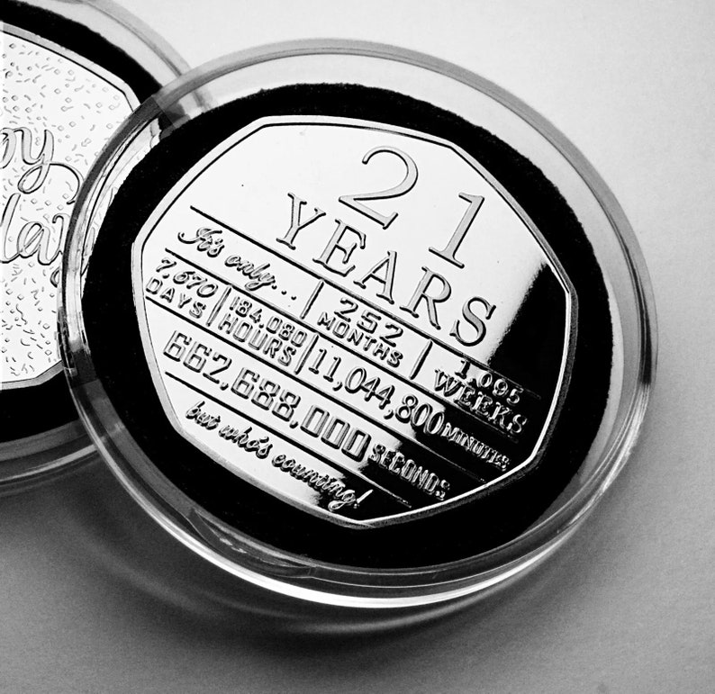 May include: A silver coin with the inscription "21 Years" and a countdown of time in days, hours, months, weeks, minutes, and seconds. The coin is in a clear plastic case.
