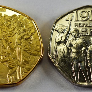 May include: Two gold-colored commemorative coins depicting the 1918 Representation of the People Act. The obverse side shows a group of people, while the reverse side shows a group of people standing with the text "1918 REPRESENTATION OF THE PEOPLE ACT".