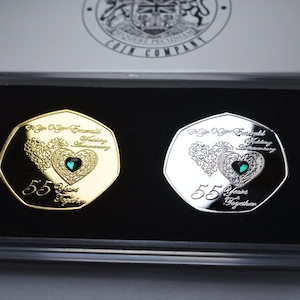 Può includere: Due monete commemorative in una custodia di velluto nero. La moneta d'oro presenta un cuore verde con l'iscrizione "For Your 55th Emerald Wedding Anniversary". La moneta d'argento presenta un cuore verde con l'iscrizione "For Your 55th Emerald Wedding Anniversary".