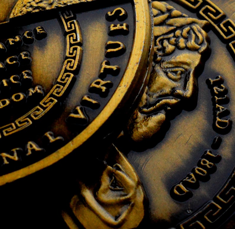 May include: Close-up of three gold-toned coins with raised lettering and a Greek key design. The coins feature the words "Seven Virtues" and "Grand 1804 121AD".