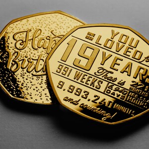 May include: Two gold-colored coins with a celebratory message. The larger coin reads "You Loved for 19 Years. That is 991 Weeks, 6,940 Days, 166,560 Hours, 9,993,240 Minutes and counting!"