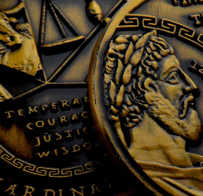 May include: Close-up of a gold-colored coin with a profile of a man with a beard and a laurel wreath on his head. The coin has a Greek key design around the edge and the words "TEMPERAT", "COURAC", "JUSTIC", "WISDO" are visible on the coin.