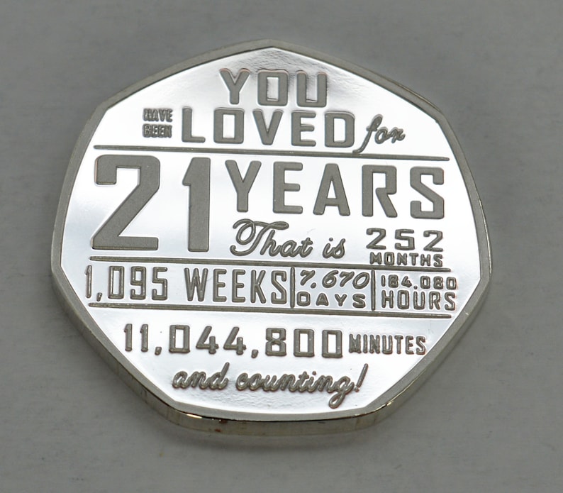 May include: A silver coin with the inscription "You Loved for 21 Years" and a breakdown of the time in weeks, days, hours, and minutes. The coin also says "That is 252 Months" and "and counting!"