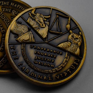 May include: A gold-toned metal coin with a black background. The coin features a design of four cardinal virtues: Temperance, Courage, Justice, and Wisdom. The coin is inscribed with "The Cardinal Virtues" around the edge.