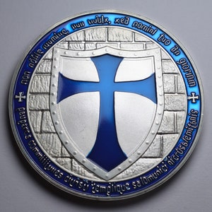 K&ouml;nnte beinhalten: Eine Silberm&uuml;nze mit einem blauen Emaille-Kreuz auf einem Schild. Die M&uuml;nze hat ein Mauerwerkdesign und den Text "non nolie ruumine. Hun mulx, xed nomini tuo an glorIAM + + peuperes commilitumes ciuisti templique salominici nicrusblemitonis" am Rand.