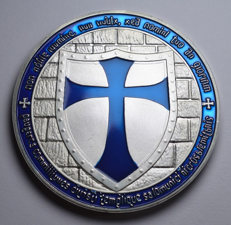 K&ouml;nnte beinhalten: Eine Silberm&uuml;nze mit einem blauen Emaille-Kreuz auf einem Schild. Die M&uuml;nze hat ein Mauerwerkdesign und den Text "non nolie ruumine. Hun mulx, xed nomini tuo an glorIAM + + peuperes commilitumes ciuisti templique salominici nicrusblemitonis" am Rand.